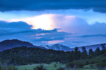 Dramatic Blue Hour Landscape with Snow-Capped Mountains and Forest
