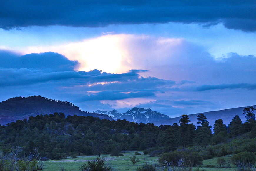 Dramatic Blue Hour Landscape with Snow-Capped Mountains and Forest
