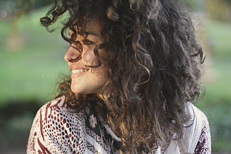 Smiling Woman with Curly Hair in Sunlight
