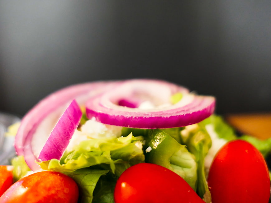 Close-up of fresh salad with red onion, tomatoes, and lettuce