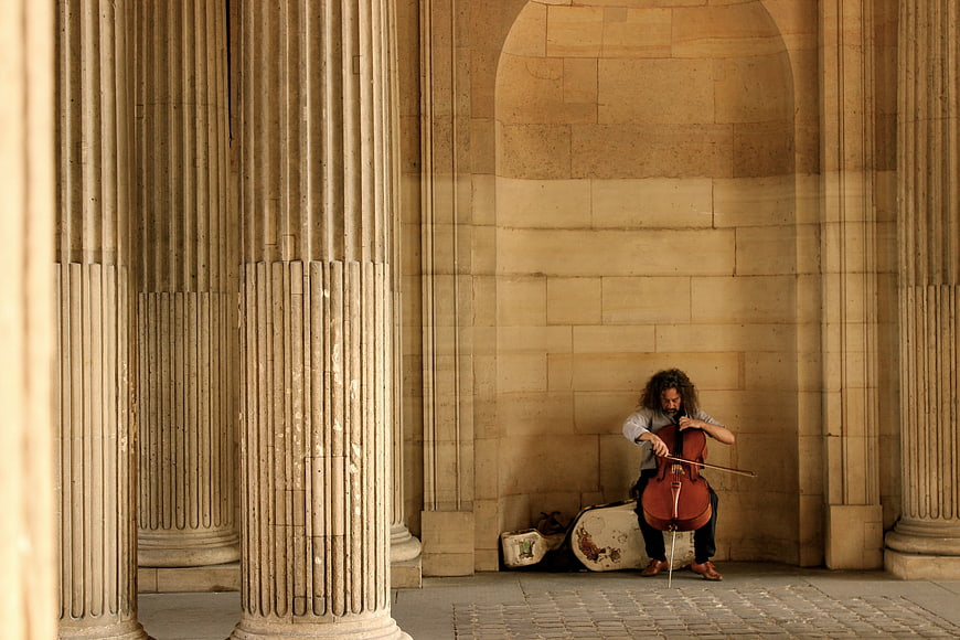 Street musician playing cello in Parisian stone archway