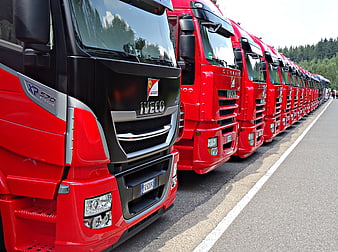 Line of red Iveco trucks parked on asphalt road