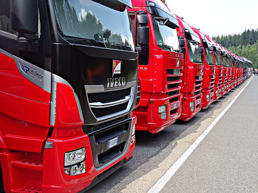 Line of red Iveco trucks parked on asphalt road
