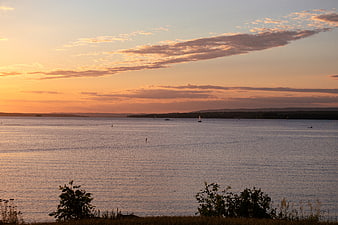 Serene Sunset Over Lake with Sailboats and Silhouetted Shoreline