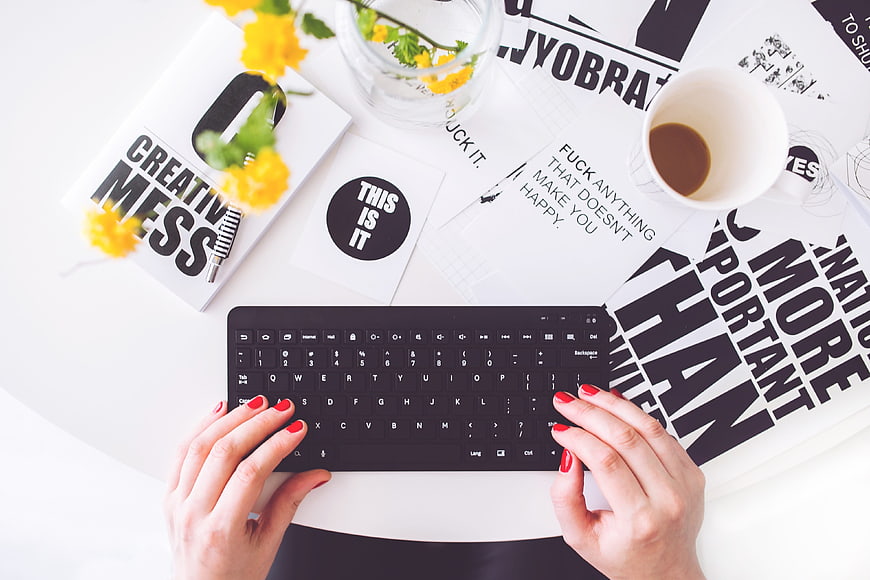 Top view of woman typing on keyboard with creative workspace