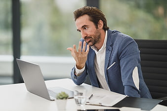 Professional businessman gesturing while working on laptop in office