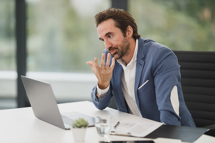 Professional businessman gesturing while working on laptop in office