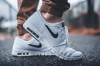 Close-up of white Nike sneakers on asphalt