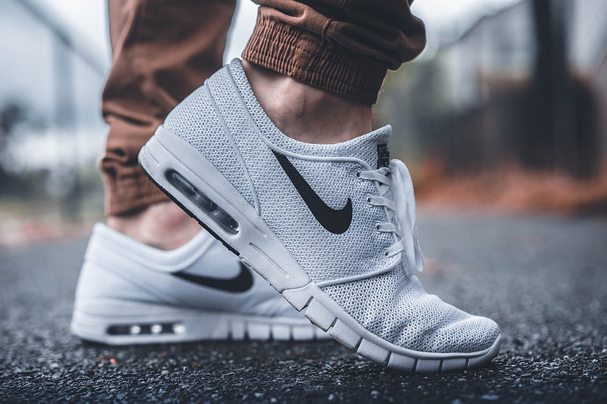 Close-up of white Nike sneakers on asphalt