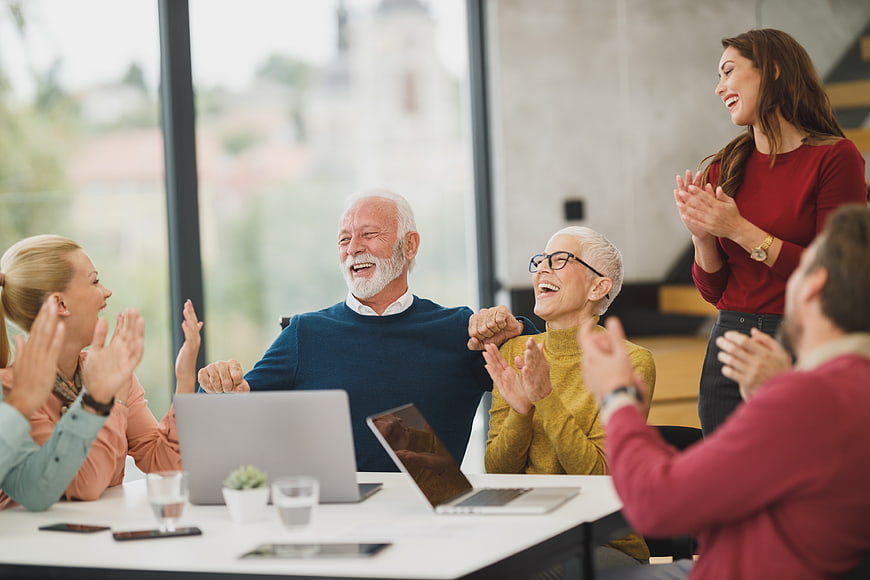 Happy multi-generational business team celebrating success in office