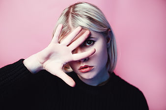 Blonde Woman Portrait With Hand Over Face Against Pink Background