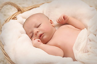 Sleeping Newborn Baby in Wicker Basket with White Blanket