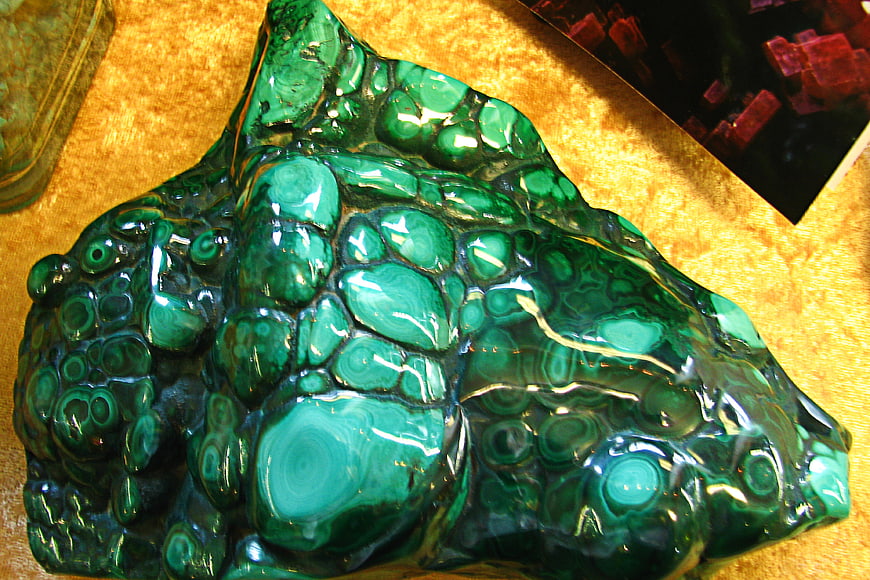Polished green malachite mineral specimen on gold background