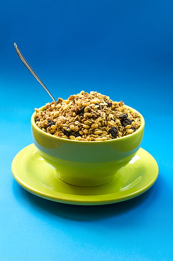 Green Bowl of Granola with Raisins on Blue Background