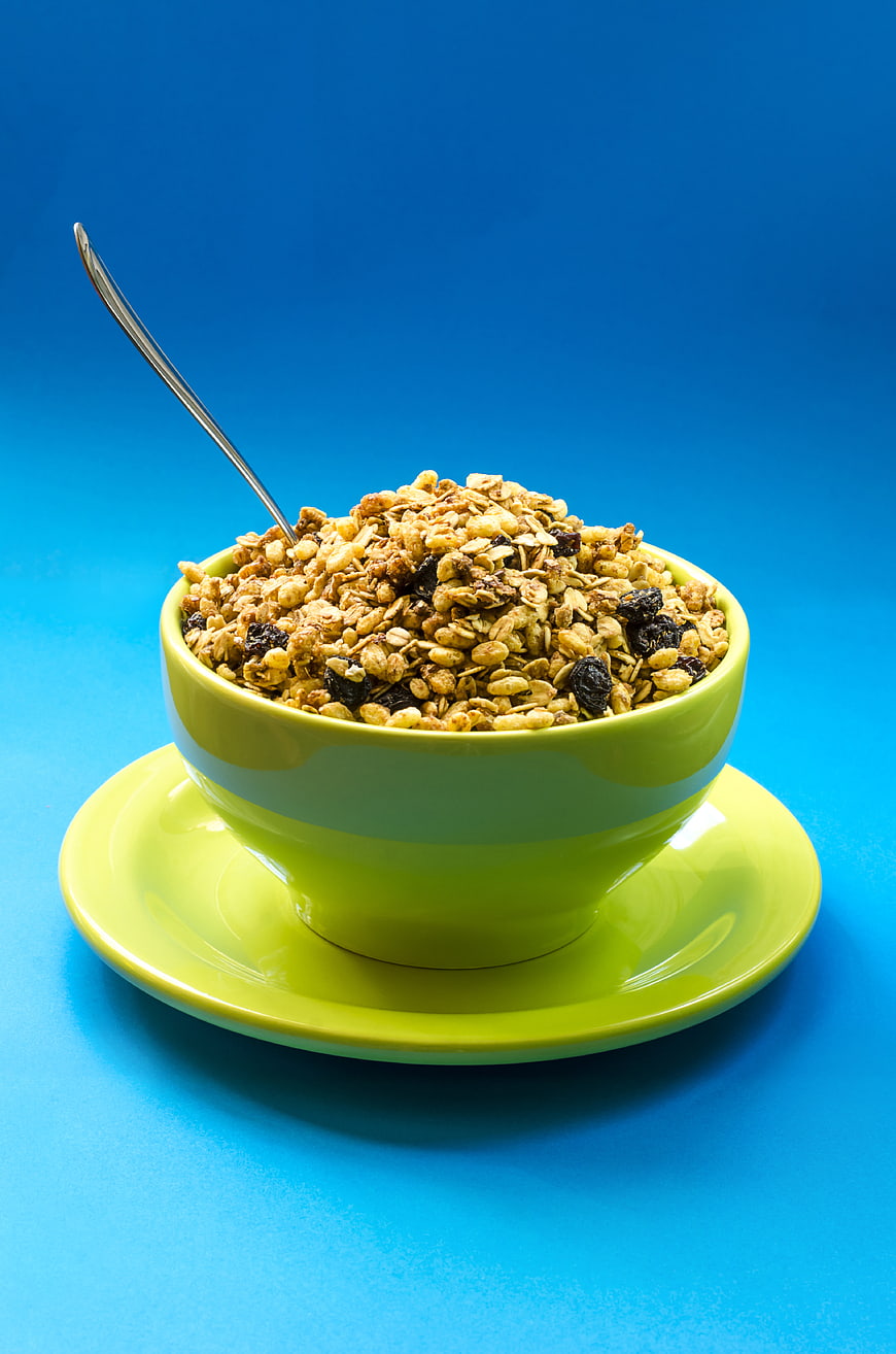Green Bowl of Granola with Raisins on Blue Background