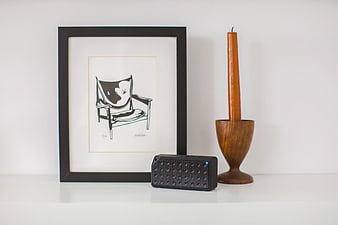 Minimalist Shelf with Black Speaker, Wooden Candle Holder, and Framed Art