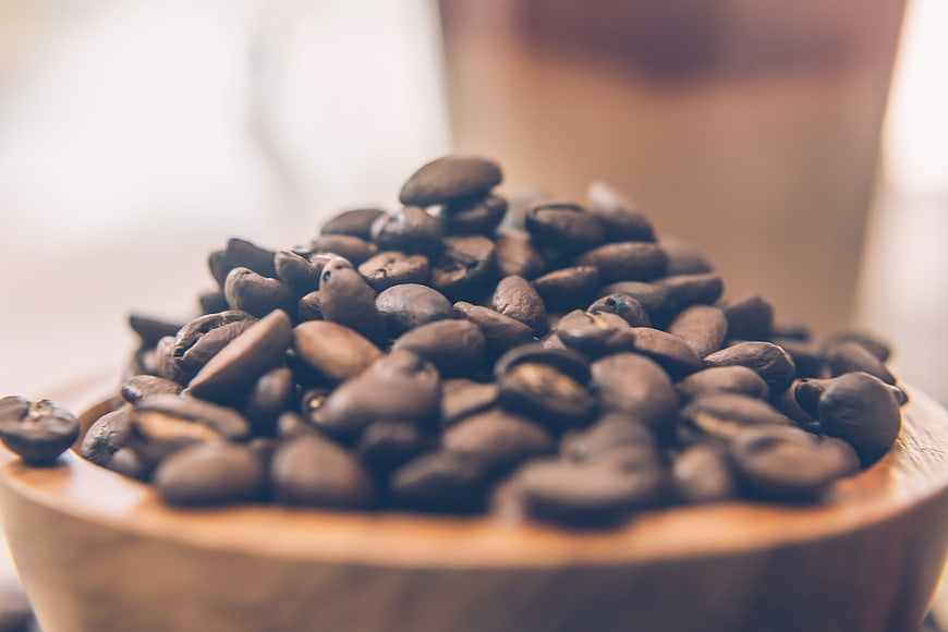 Close-up of roasted coffee beans in a wooden bowl