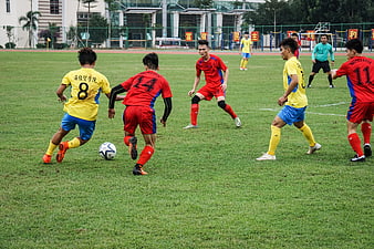 Young Men Playing Soccer Match on Grass Field