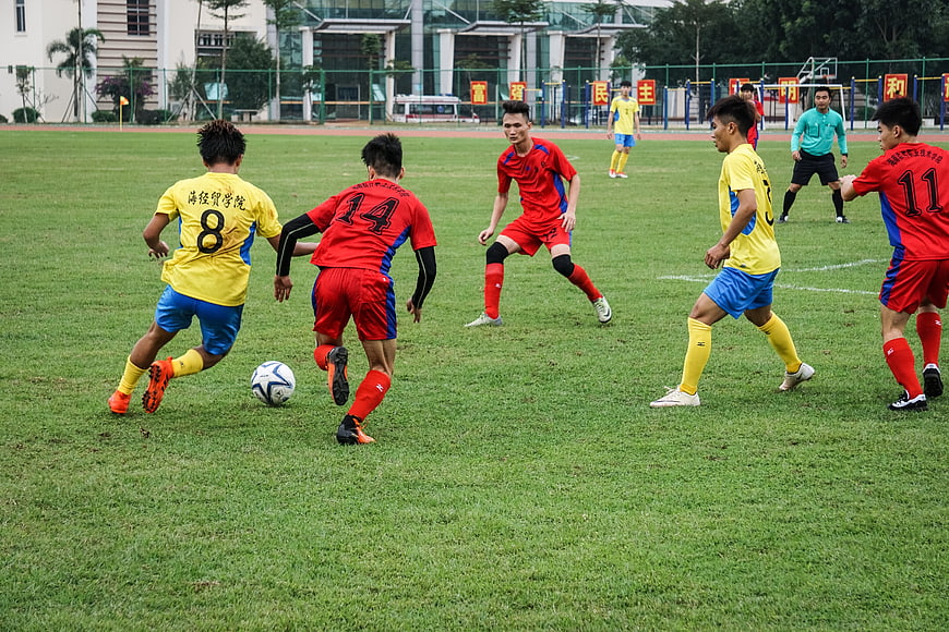 Young Men Playing Soccer Match on Grass Field