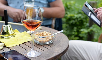 Glass of rosé wine and peanuts on outdoor wooden table