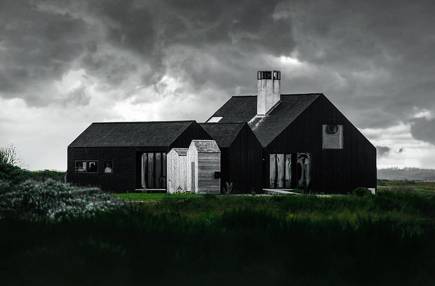 Modern Black House in Rural Landscape Under Stormy Sky