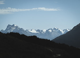 Snow-capped mountain range with dark forested foreground
