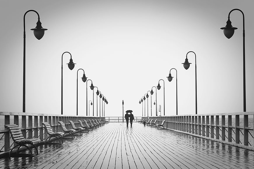 Silhouetted Couple Walking on Rainy Pier with Umbrella