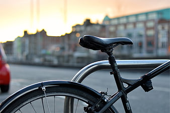 Close-up of black bicycle seat and rear wheel at sunset