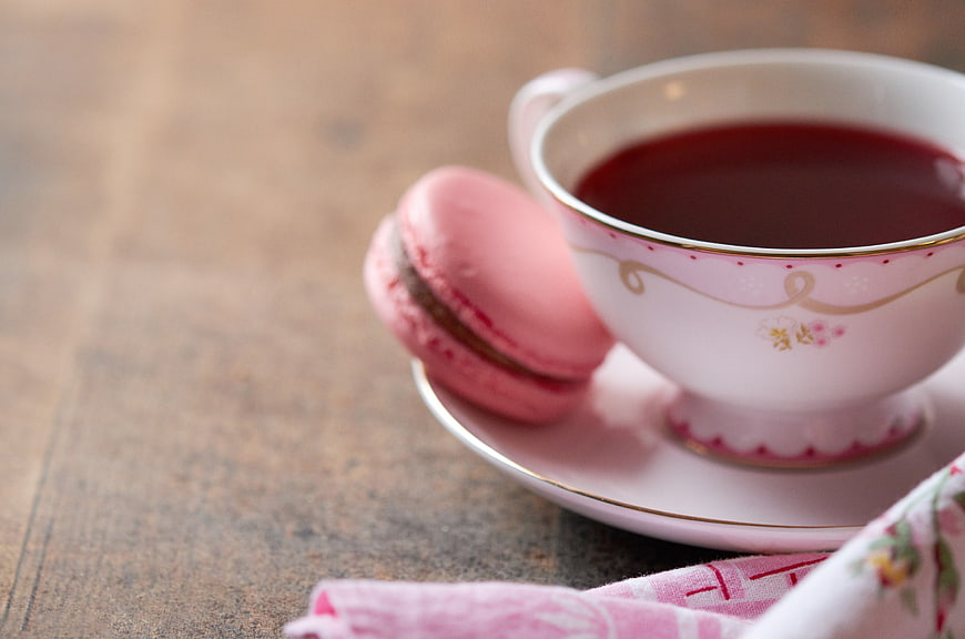 Pink macaron and tea cup on rustic wooden table