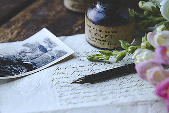 Vintage violet ink bottle, fountain pen, and handwritten letter with flowers