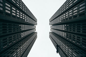Symmetrical low angle view of modern skyscrapers against white sky