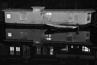 Black and white night photo of a Dutch houseboat with reflection