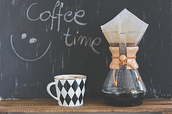 Pour-over coffee maker and patterned mug on wooden table