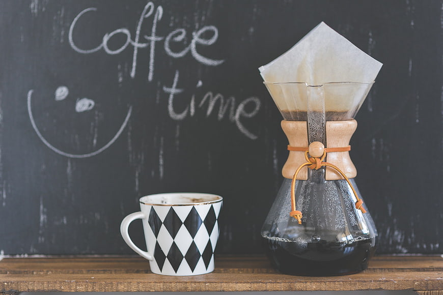 Pour-over coffee maker and patterned mug on wooden table
