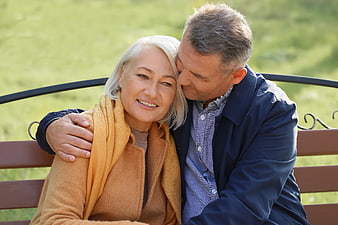Senior couple embracing on park bench in sunlight