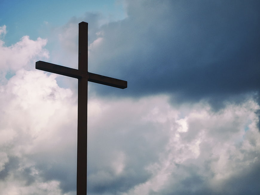 Silhouette of wooden cross against dramatic cloudy sky