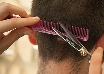 Close-up of barber cutting hair with scissors and comb