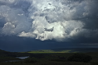 Dramatic Storm Clouds Over Green Rolling Hills Landscape