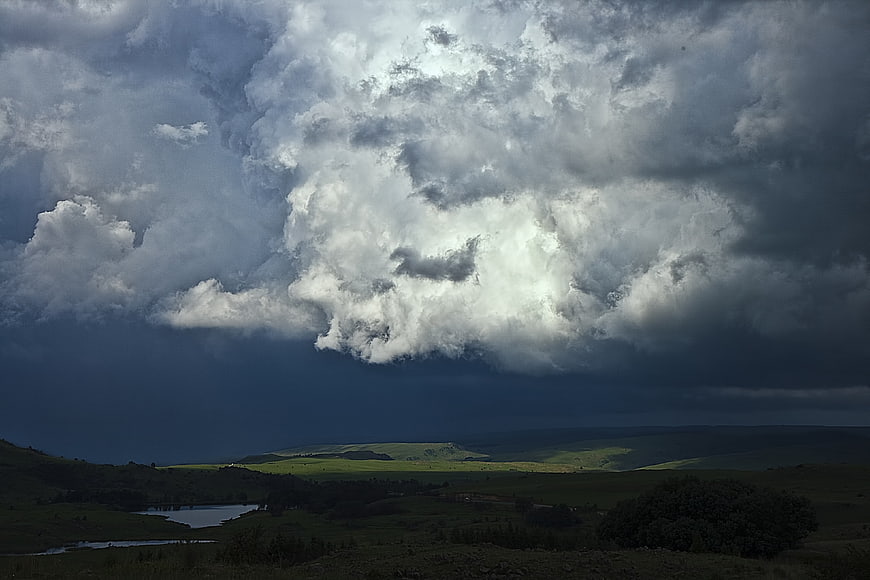Dramatic Storm Clouds Over Green Rolling Hills Landscape