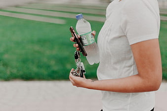 Woman Holding Water Bottle, Keys, and Smartphone
