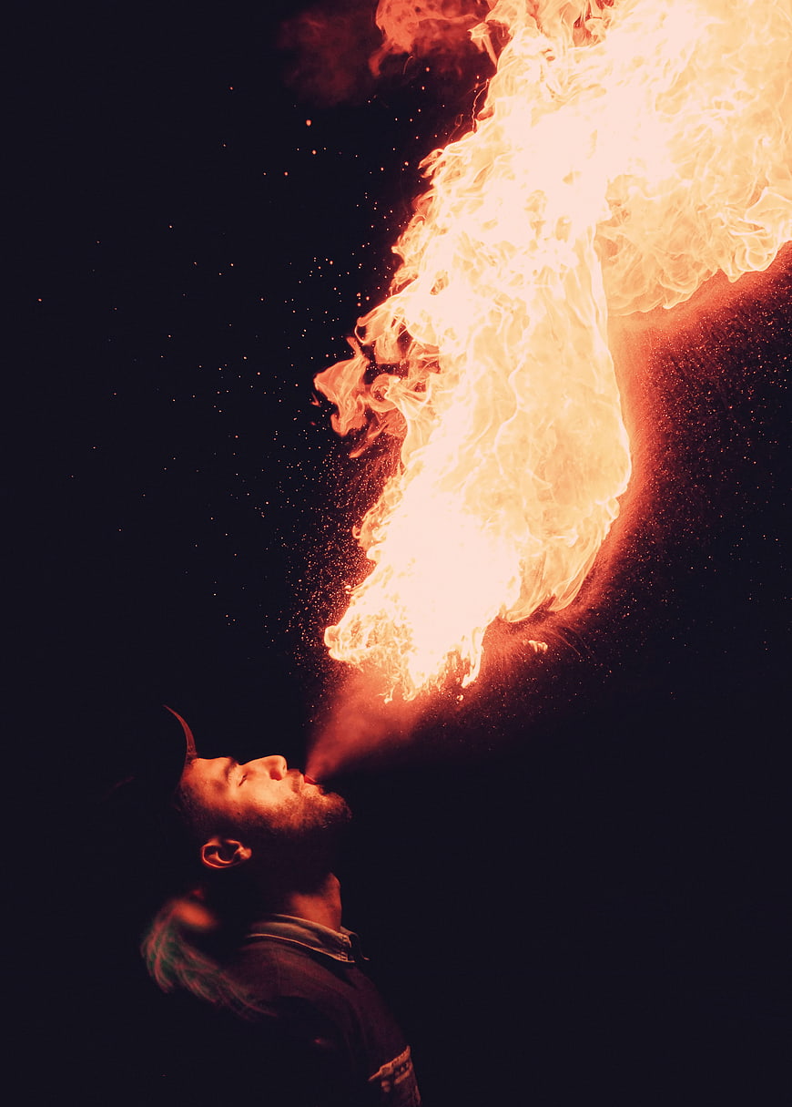 Man breathing fire against dark background
