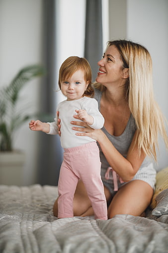 Happy Mother Holding Toddler Daughter on Bed