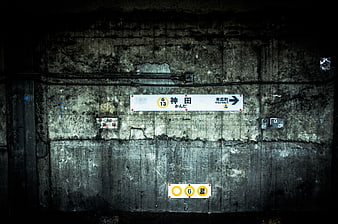 Dark textured concrete wall with Japanese subway station signs