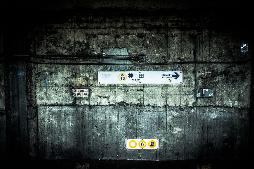Dark textured concrete wall with Japanese subway station signs