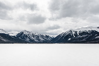 Snowy Mountain Landscape with Frozen Lake and Cloudy Sky