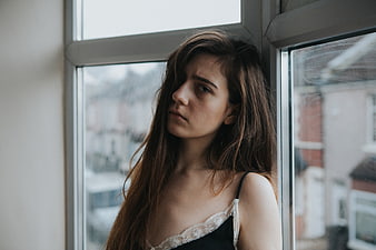 Melancholic woman looking out window in black lace top