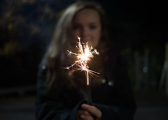 Woman holding sparkler at night with blurred face