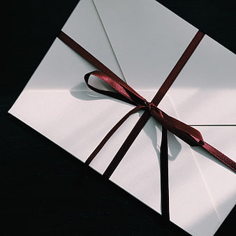 White Envelope With Dark Red Ribbon On Black Background