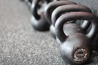 Row of black cast iron kettlebells on gym floor