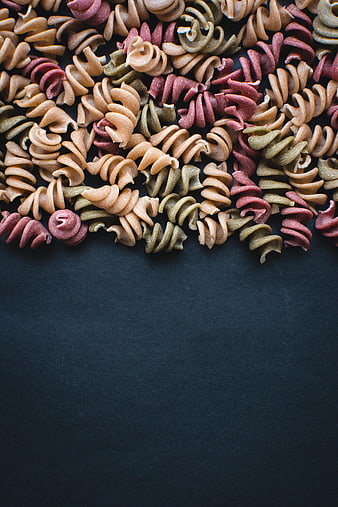 Colorful tricolor fusilli pasta on dark background